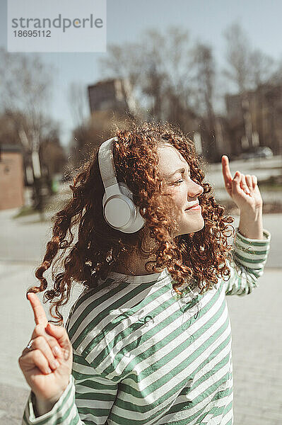 Frau tanzt und hört Musik über Bluetooth-Kopfhörer