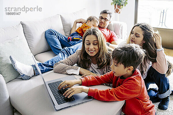 Junge benutzt Laptop von Familie  die zu Hause im Wohnzimmer sitzt