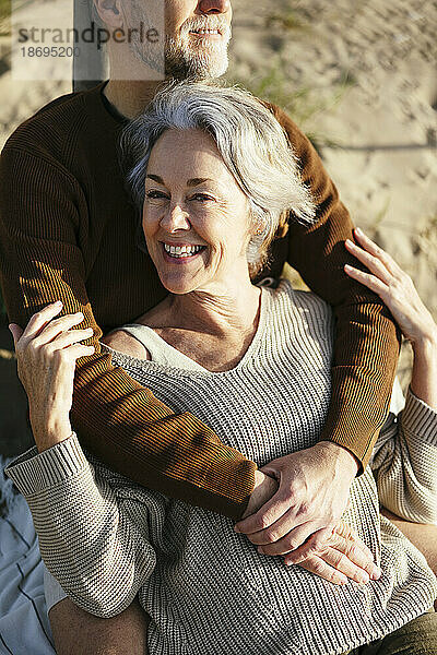 Fröhliche Frau umarmt von Mann am Strand