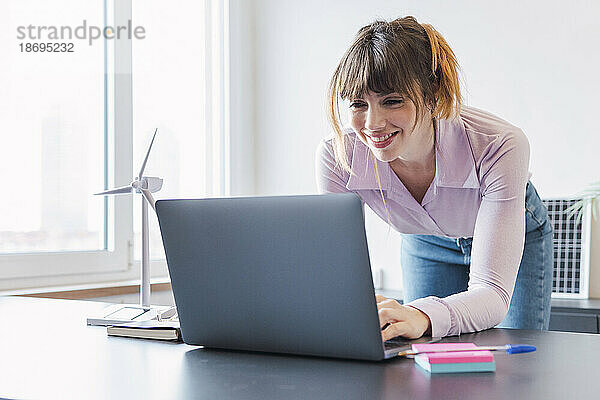 Glückliche Geschäftsfrau  die am Schreibtisch am Laptop arbeitet