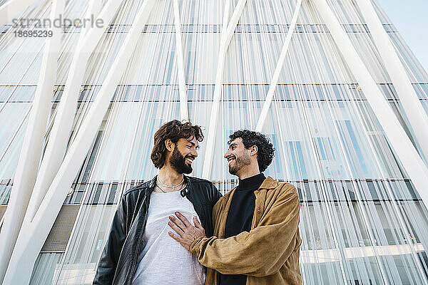 Romantic gay couple standing in front of building