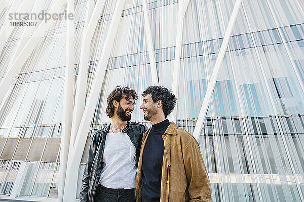 Schwule Männer schauen sich gegenseitig an  während sie vor einem Gebäude stehen