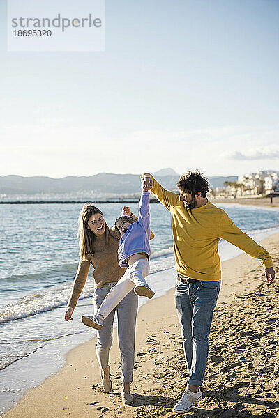 Vater und Mutter holen Tochter am Strand ab