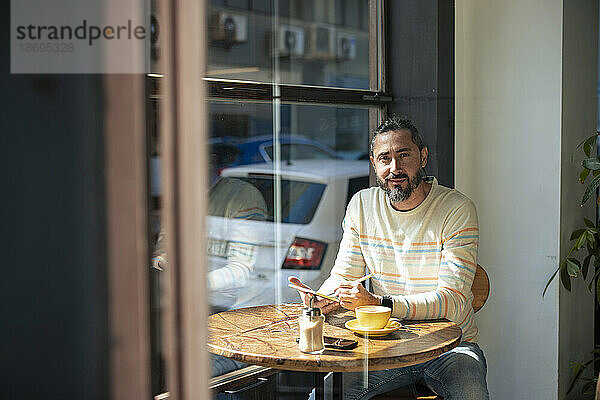 Mann mit Tablet-PC sitzt am Tisch im Café