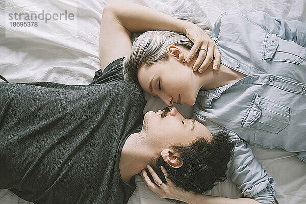 Mann und Frau liegen auf dem Bett und umarmen sich