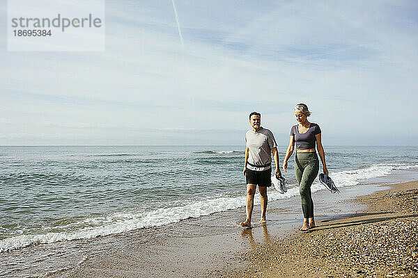 Älteres Paar spaziert am Strand auf Sand am Meer