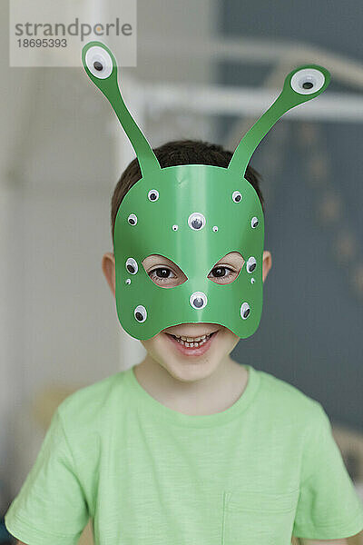 Lächelnder Junge mit grüner Alienmaske