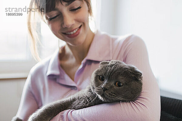 Lächelnde Frau hält Katze im Arm