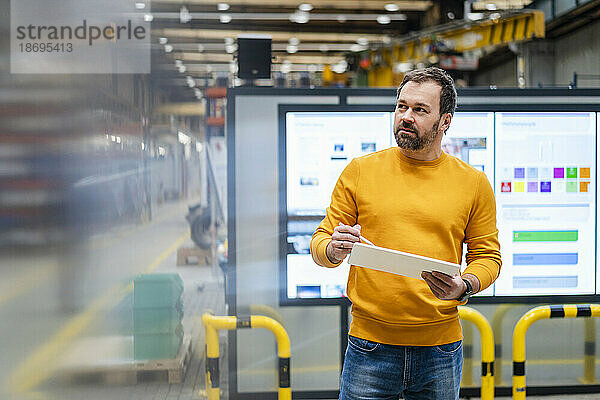 Reifer Mann hält Tablet-PC in der Fabrik