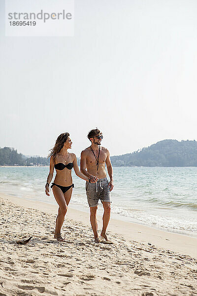 Paar spaziert auf Sand am Strand