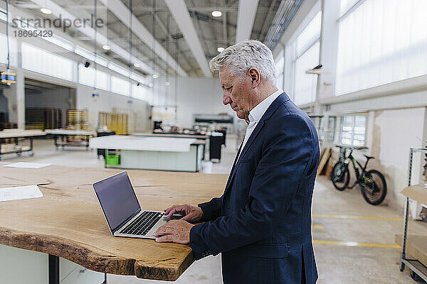 Geschäftsmann benutzt Laptop auf Werkbank in Fabrik
