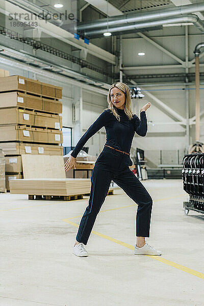 Lächelnde Geschäftsfrau tanzt in Tischlerei