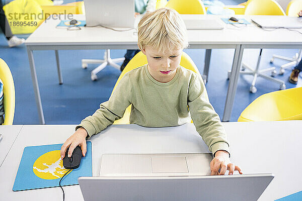 Junge benutzt Laptop am Schreibtisch im Computerunterricht