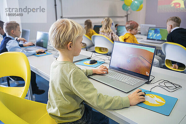 Junge lernt am Laptop und sitzt im Computerunterricht in der Schule