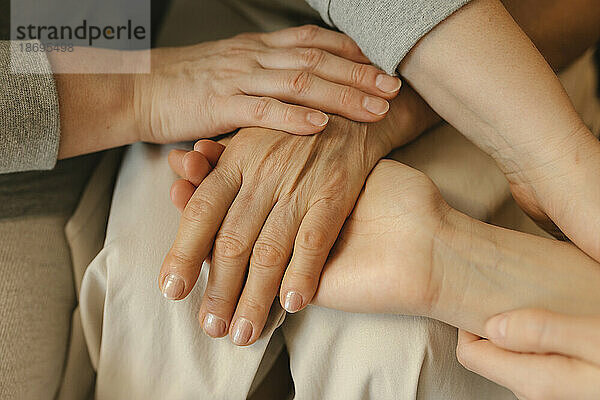 Elderly woman stacking hands with family at home