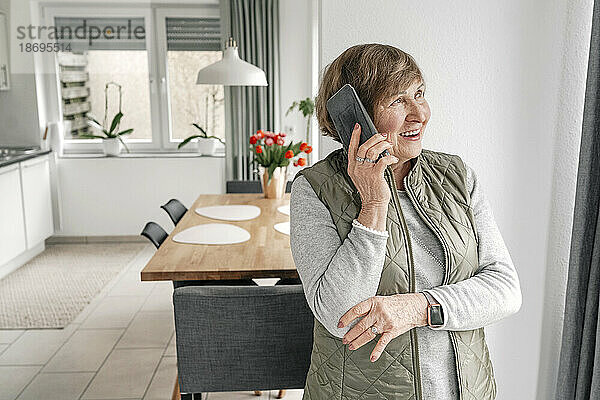 Ältere Frau telefoniert zu Hause mit dem Smartphone