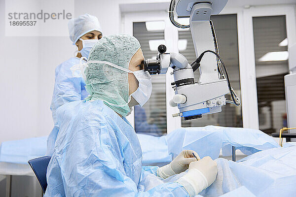 Chirurg führt Augenoperation mit Mikroskop im Operationssaal durch