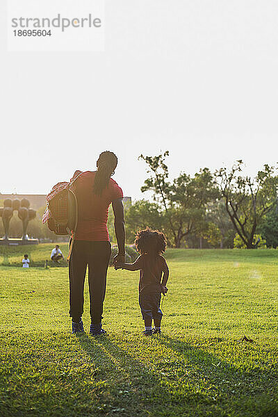 Vater und Sohn stehen an einem sonnigen Tag auf Gras im Park