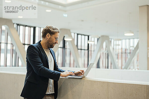 Geschäftsmann arbeitet mit Laptop an der Wand