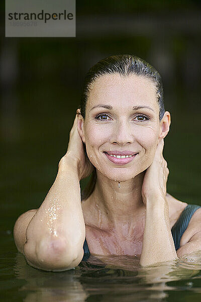 Smiling woman with wet hair in lake