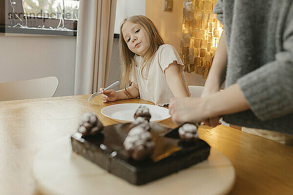 Mädchen betrachtet Schokoladenkuchen auf dem Tisch
