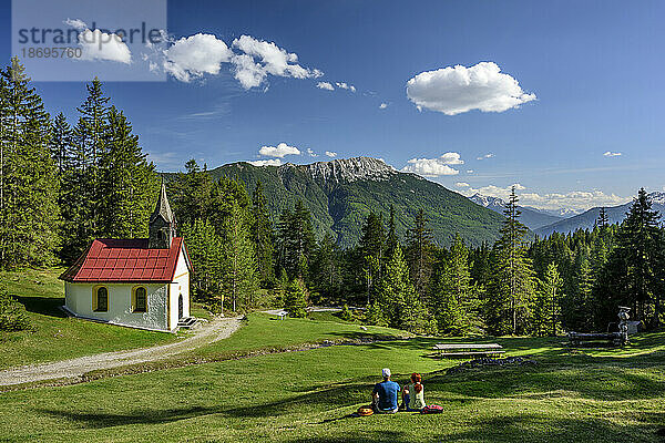 Österreich  Tirol  Wanderpaar rastet vor der Alpenkapelle aus
