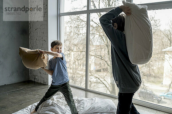 Brothers doing pillow fight at home