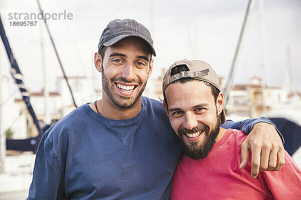 Lächelnde Männer mit Mützen im Hafen