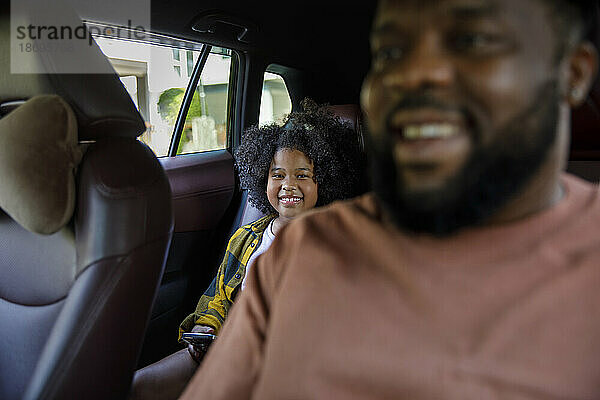 Lächelnder Vater und Tochter sitzen im Auto