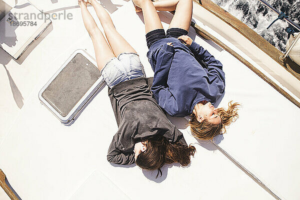 Freunde liegen an einem sonnigen Tag auf dem Bootsdeck