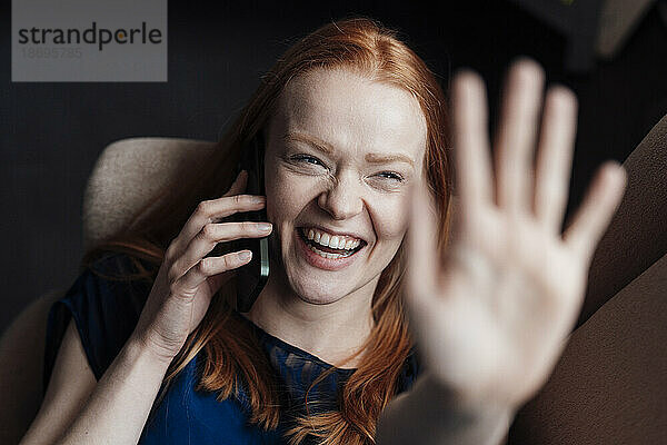Happy woman showing palm and talking on smart phone