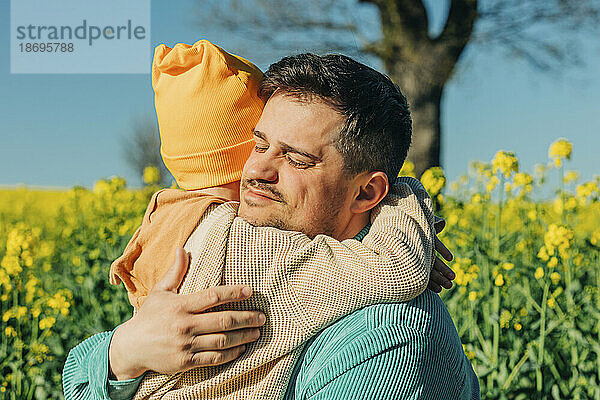 Vater und Sohn umarmen sich am Rapsfeld