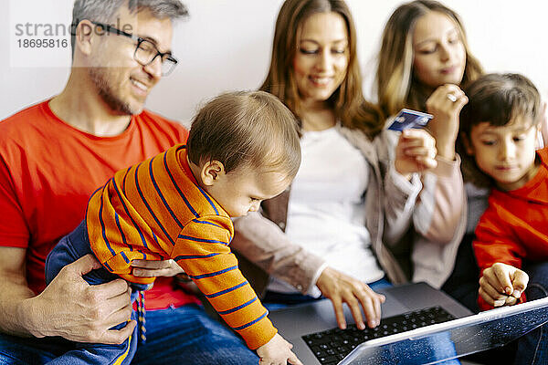 Familie verbringt gemeinsam Freizeit mit Laptop zu Hause