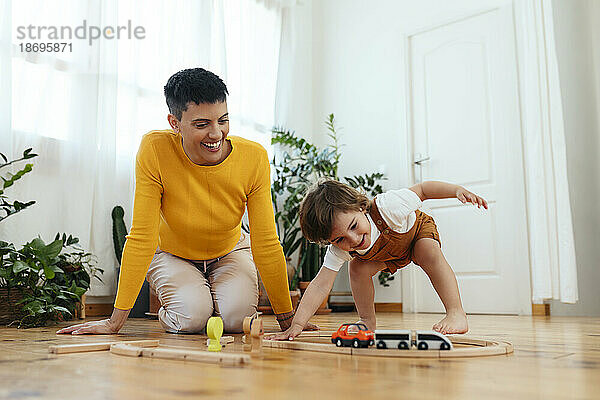 Glücklicher Sohn  der zu Hause mit der Spielzeugeisenbahn von der Mutter spielt