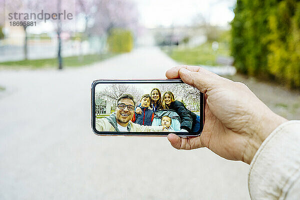 Mann macht Selfie per Handy mit Familie im Park