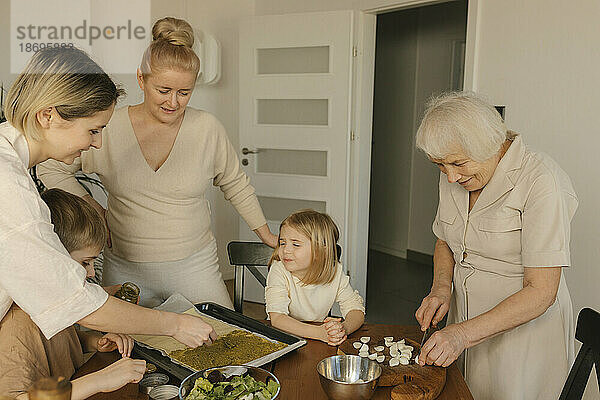 Mehrgenerationenfamilie kocht zu Hause gemeinsam Essen