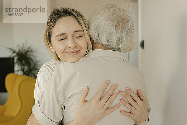 Lächelnde Frau umarmt Großmutter zu Hause