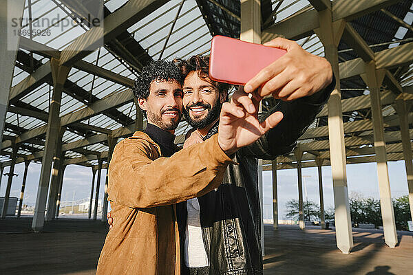 Gay men taking selfie through smart phone under concrete structure