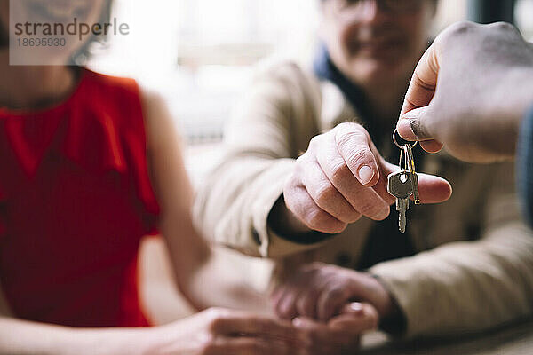 Immobilienmakler übergibt Hausschlüssel an Paar