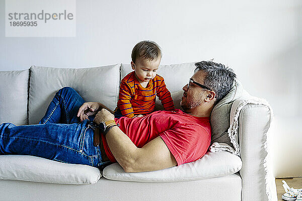Vater liegt mit Sohn zu Hause auf dem Sofa
