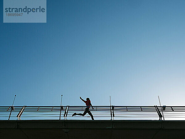 Sportler läuft in der Nähe des Geländers unter strahlend blauem Himmel