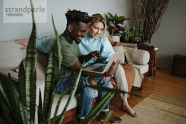 Lächelnder Mann teilt Laptop mit Freundin zu Hause