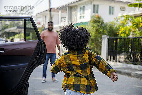 Mädchen rennt auf den Vater zu  der auf der Straße steht