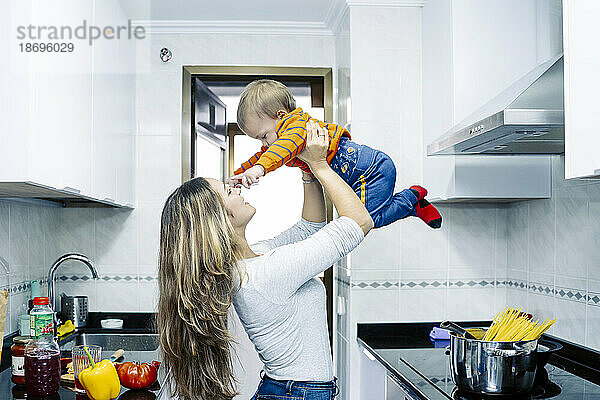 Verspielte Schwester holt kleinen Jungen zu Hause in der Küche ab