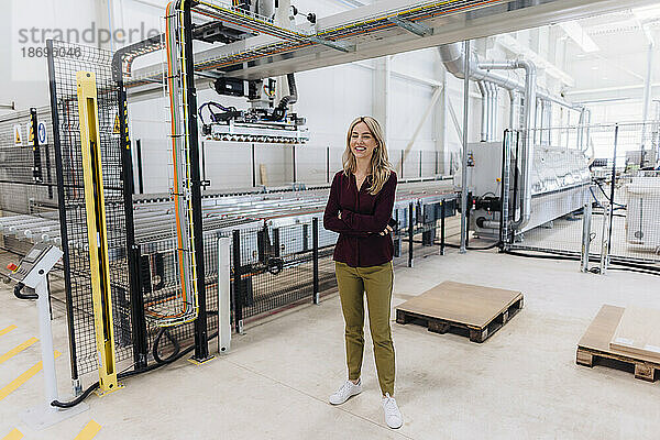 Lächelnde Geschäftsfrau steht in der Fabrik