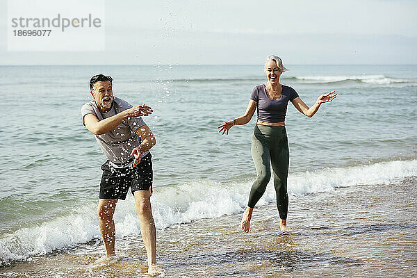 Verspieltes Paar genießt das Meer am Strand