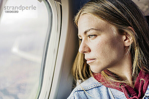 Junge Frau schaut aus dem Flugzeugfenster