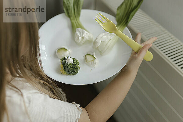 Mädchen hält Gemüse auf Teller