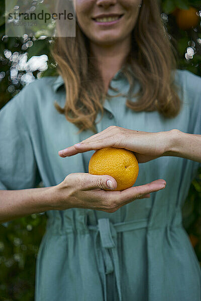 Frau hält reife Orange in der Hand