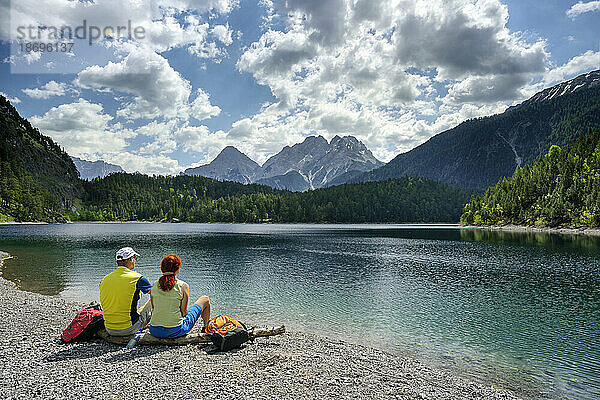 Österreich  Tirol  Wanderpaar entspannt am Ufer des Blindsees